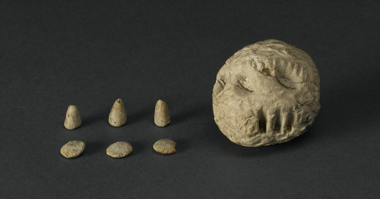 Clay ball with imprints on the outside, three small clay disks, and three small clay cones